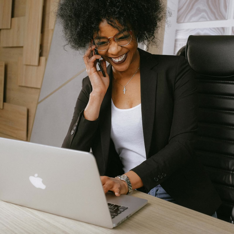 Smiling woman having a phone consultation, sitting indoors and looking relaxed and engaged in conversation.